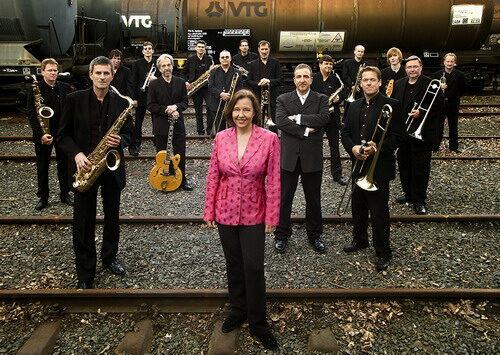 Foto: Orchester der HCC Bigband steht mit Instrumenten auf Bahngleisen