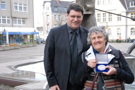 Bürgermeister Hans-Peter Haupt und Therèse Le Norcy mit Silbermedaille vor Rathausbrunnen